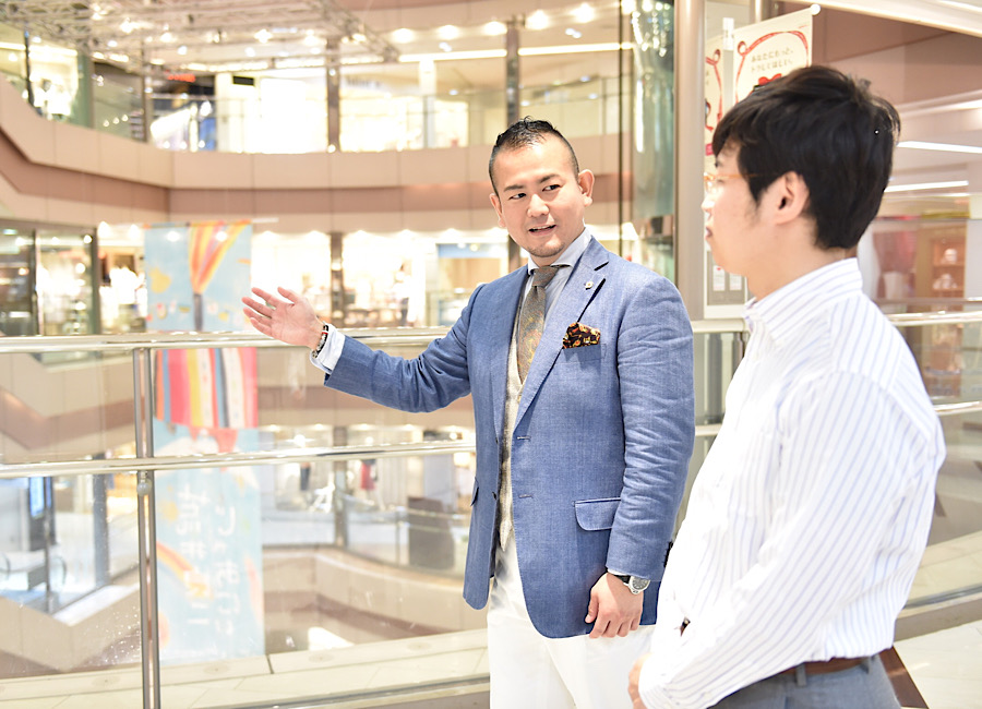 明るい売場でお客様と会話しながら装いを提案するコバヤシシゲユキ