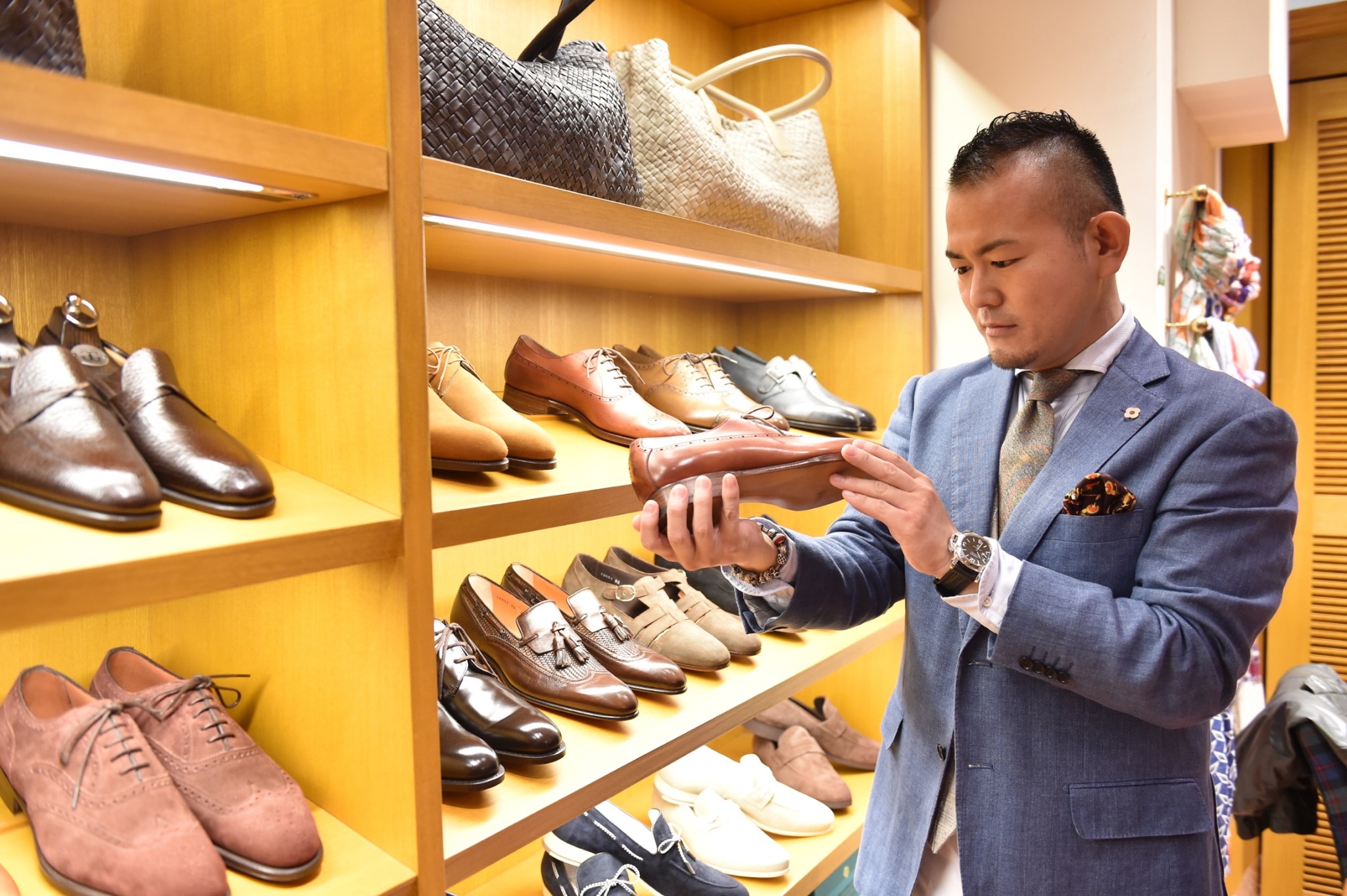 店舗で革靴を手に取り確認するパーソナルスタイリスト小林茂之